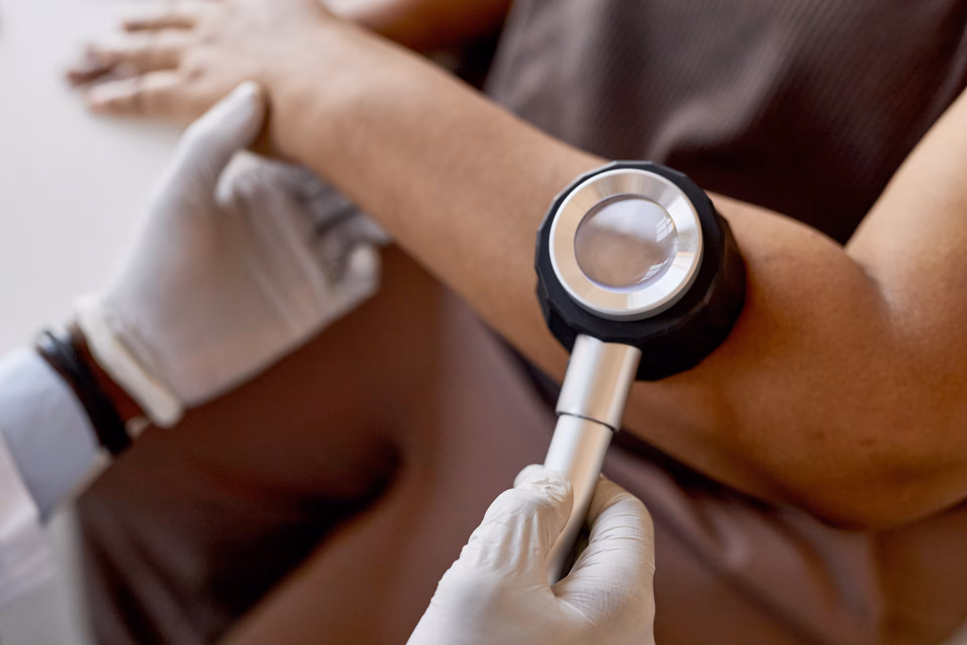 Close up of doctor holding dermatoscope while examining skin of patient at dermatology clinic